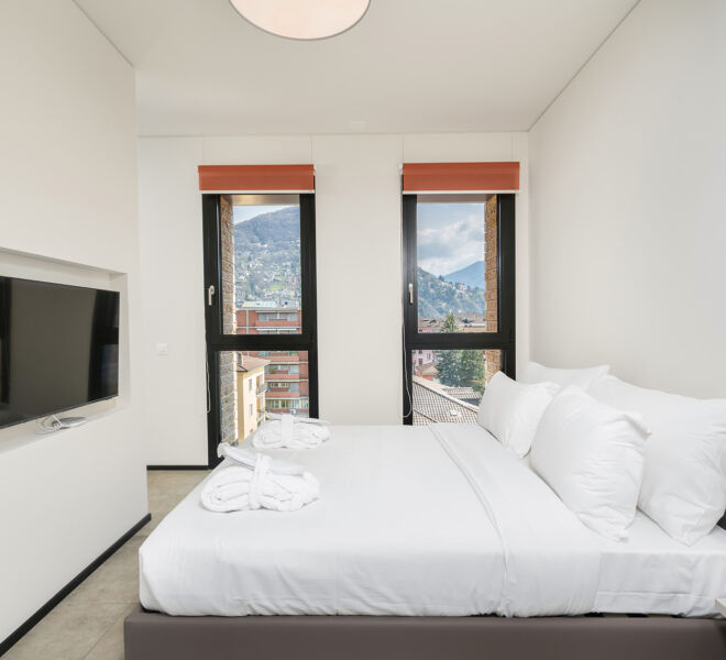 Schlafzimmer und Blick auf die Fenster in der Einzimmerwohnung in Lugano Swiss Hotel Apartments